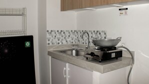 A kitchen with a built-in stove, a sink, and a microwave. - Nice And Spacious 3Br At Meikarta Apartment (Cikarang)