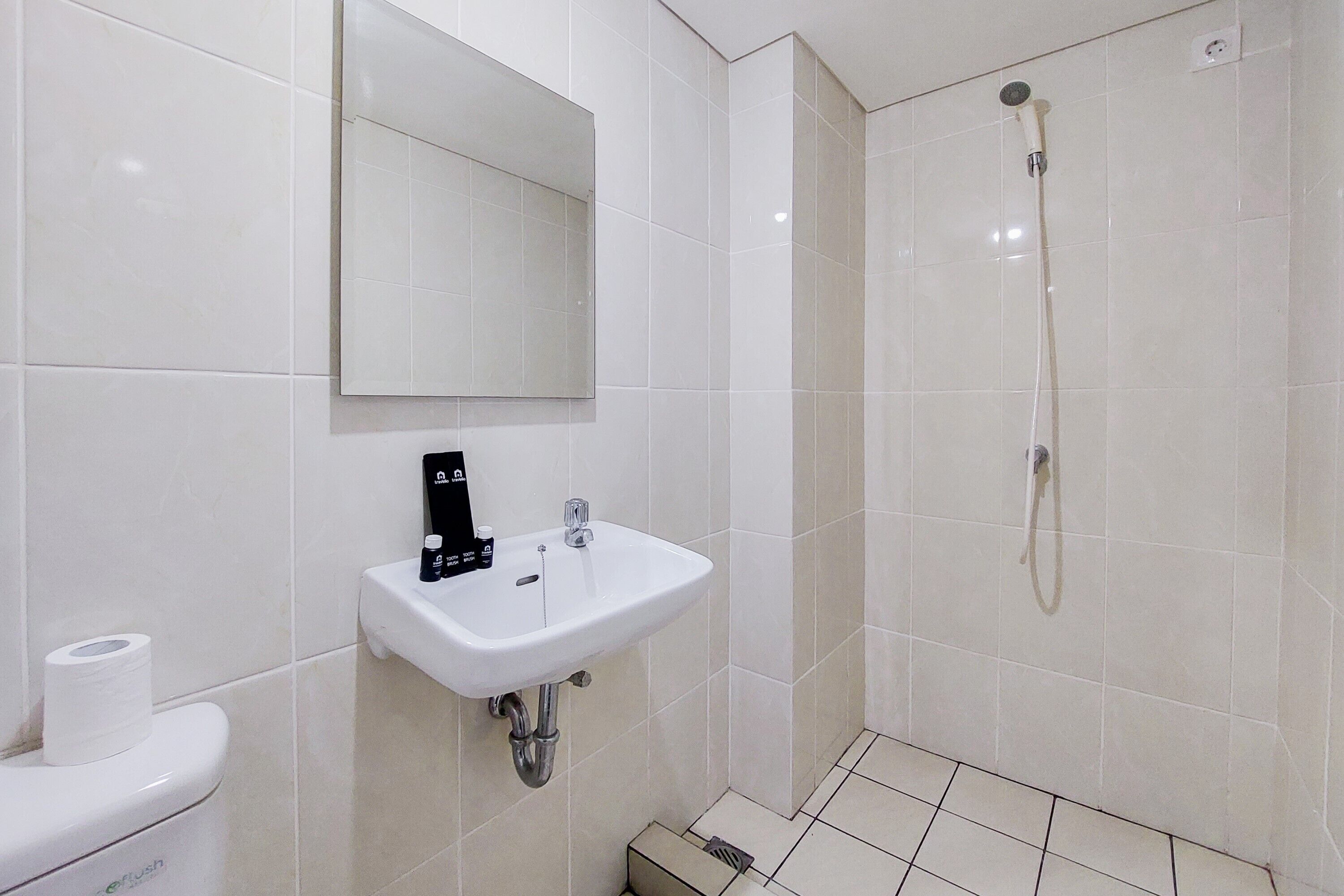 A bathroom with a white sink, a mirror, a toilet, and a shower.