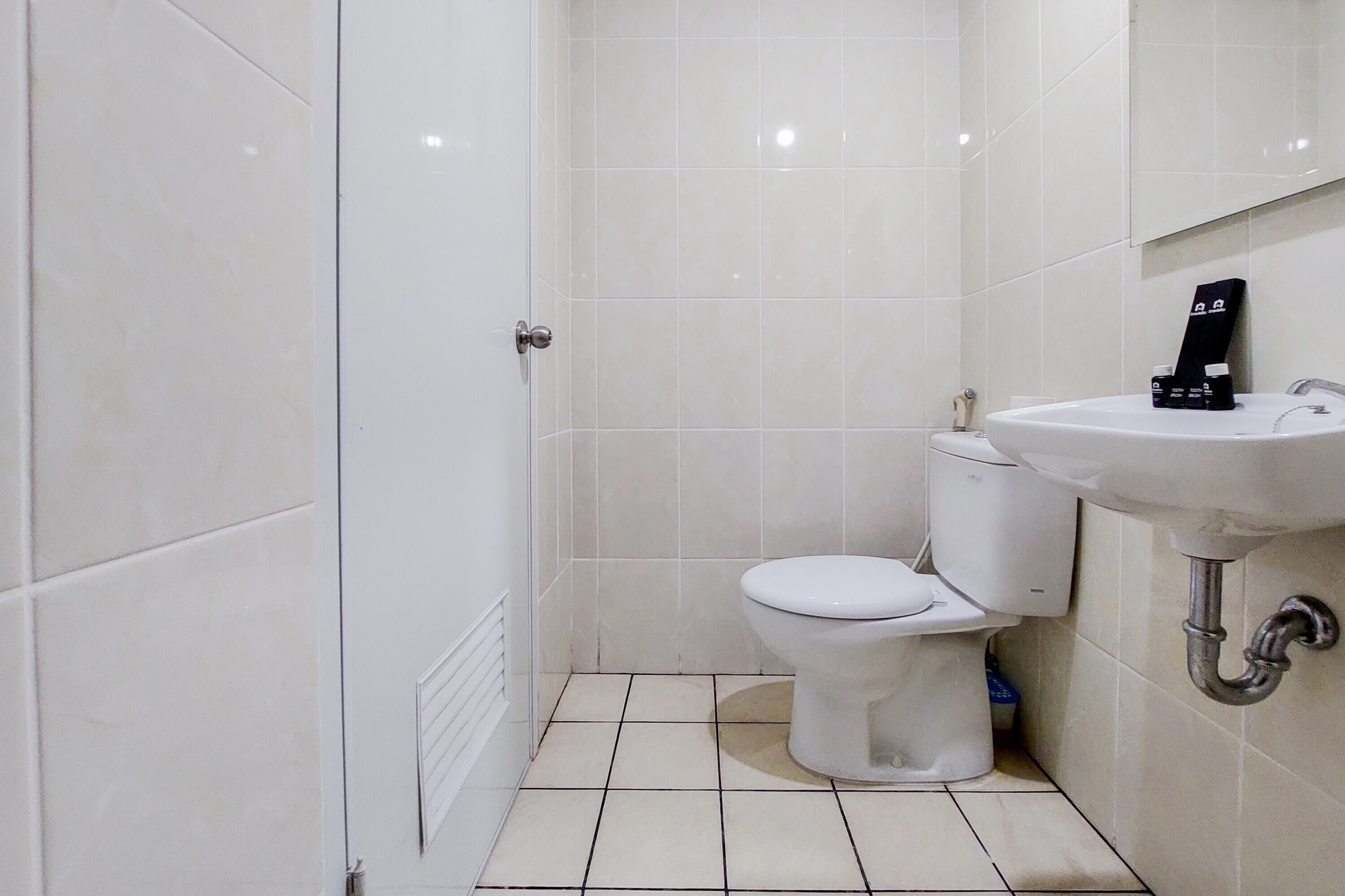 A bathroom with a toilet, sink, and tiled walls.