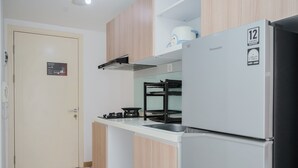 A compact kitchen with a built-in oven, a refrigerator, and a sink. - Nice And Comfort Studio At M-Town Residence Apartment (Gading Serpong)