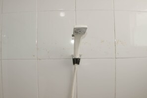 A white showerhead mounted on a tiled wall.