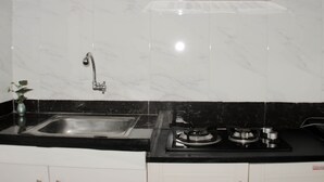 A kitchen with a sink, stove, and ventilation hood. - Minimalist And Homey 1Br At Bassura City Apartment (Jakarta)