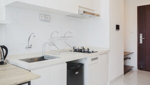 A modern kitchen with white cabinetry, a stainless steel sink, a built-in stove, and a dishwasher. - Comfrot 2Br At Sky House Bsd Apartment (Pagedangan)