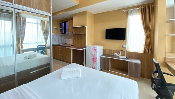 Ein Hotelzimmer mit einem Bett, einem Schreibtisch, einem Fernseher und einer Küchenzeile.