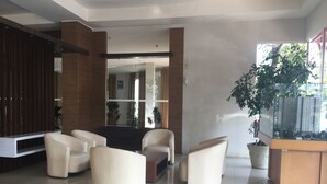 A modern living room with a sofa set, a coffee table, and a TV unit. There is a large window with a view of buildings outside. - Cozy 2Br At Pinewood Apartment Jatinangor (Cileunyi)