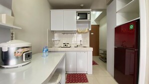 A compact kitchen with a microwave, a rice cooker, a sink, and a refrigerator. - Cozy 2Br At Pinewood Apartment Jatinangor (Cileunyi)