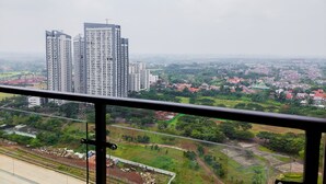Un edificio de gran altura con varios pisos, rodeado de zonas residenciales y terrenos sin urbanizar.