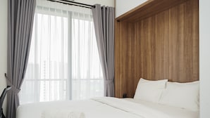 Une chambre d’hôtel avec un grand lit, des rideaux gris et une tête de lit en bois.