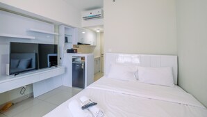 A modern hotel room with a bed, a TV, a minibar, and a small kitchenette. - Nice And Comfy Studio At Springlake Summarecon Apartment (Bekasi)