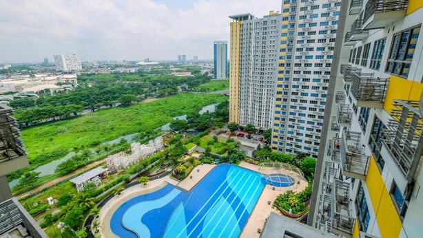 A high-rise building with a swimming pool and surrounding greenery. - Nice And Comfy Studio At Springlake Summarecon Apartment (Bekasi)