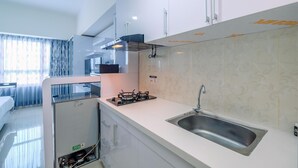 A modern kitchen with a stainless steel sink, a gas stove, and white cabinetry. - Nice And Comfy Studio At Springlake Summarecon Apartment (Bekasi)