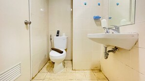 A small, clean bathroom with a toilet, sink, and mirror. - Spacious Studio Room Apartment At Parahyangan Residence (Bandung)