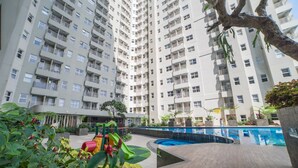 A high-rise residential building with multiple balconies, a swimming pool, and a children's play area. - Spacious Studio Room Apartment At Parahyangan Residence (Bandung)