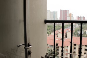 Blick vom Balkon mit Metallgeländer auf eine Stadtlandschaft mit Gebäuden und Bäumen.
