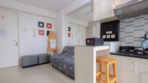 A compact living space with a kitchenette, a sofa bed, and a small dining area. - Comfort And Warm 2Br At Bassura City Apartment (Jakarta)