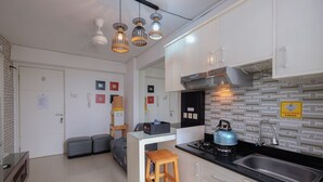 A compact kitchen with a gas stove, stainless steel sink, and modern pendant lights. - Comfort And Warm 2Br At Bassura City Apartment (Jakarta)