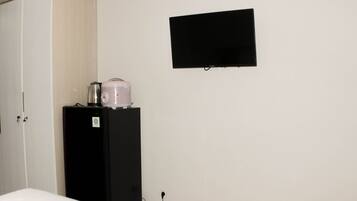 Une chambre comprenant un lit, une armoire, un réfrigérateur noir et un téléviseur à écran plat fixé au mur.