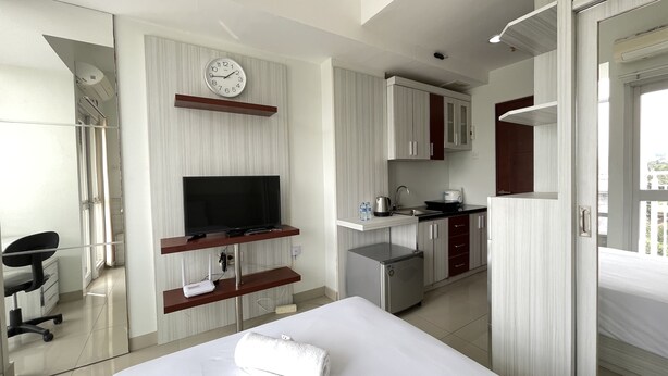 Una habitación de hotel moderna con cama, televisión, una pequeña kitchenette y baño.