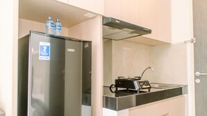 Una cocina compacta con un refrigerador de acero inoxidable, una estufa a gas y un lavabo.