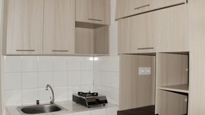 Een moderne keuken met witte tegels, houten kastjes, een roestvrijstalen spoelbak en een ingebouwd fornuis.