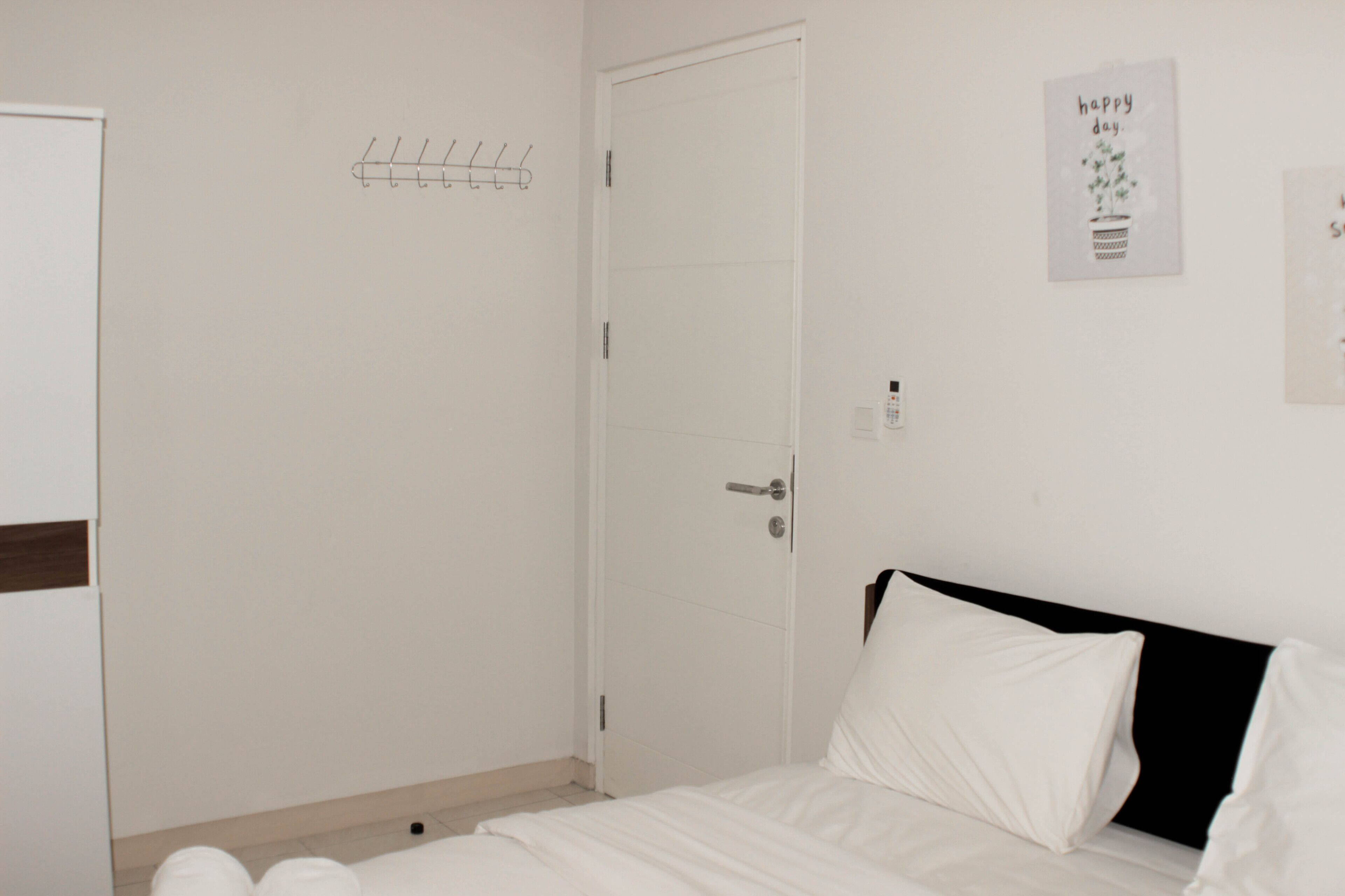Une chambre à coucher avec un lit, une porte et un crochet fixé au mur.