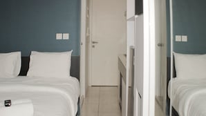 Een hotelkamer met twee bedden, een badkamer en een klein bureau.
