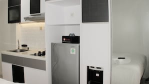Een kleine keuken met een ingebouwde spoelbak, een roestvrijstalen koelkast en een compact fornuis.