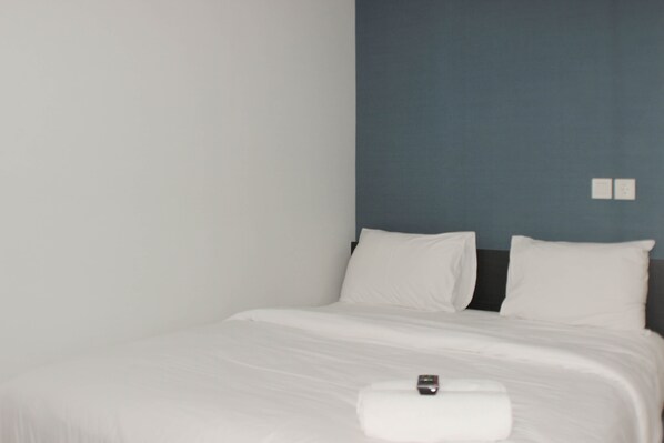 A neatly made bed with white linens and a remote control on the footboard. - Best Choice Studio Room At Springlake Summarecon Bekasi Apartment (Bekasi)