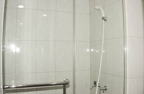 A shower area with white tiled walls and a glass door. - Best Choice Studio Room At Springlake Summarecon Bekasi Apartment (Bekasi)