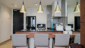 Een moderne keuken met een centraal eiland, drie hanglampen en een zithoek met drie stoelen.
