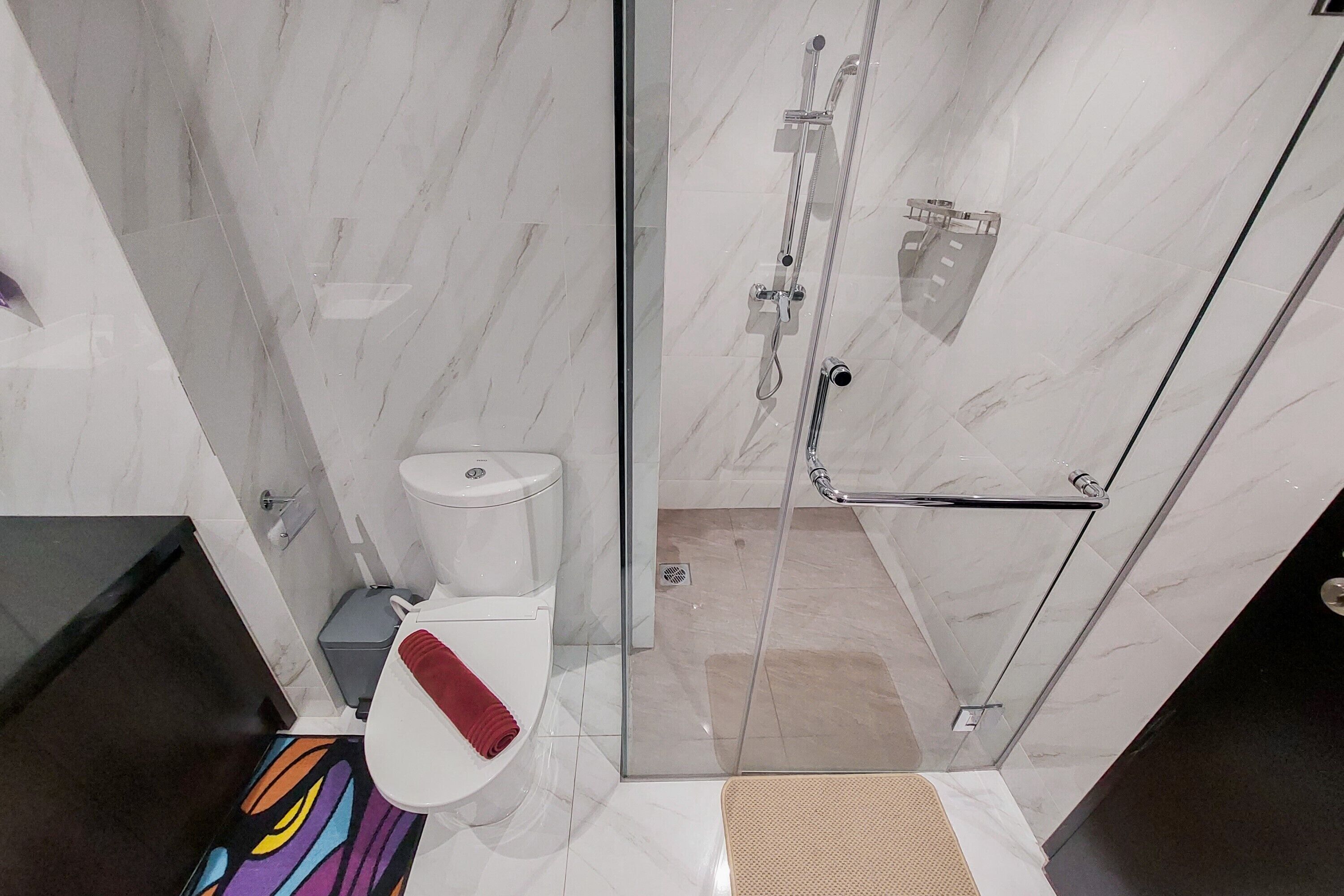 A modern bathroom with a glass shower enclosure, a toilet, and a sink.