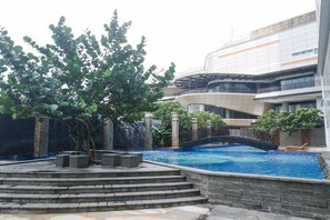 Un edificio moderno con piscina, escalones de piedra y un puente.
