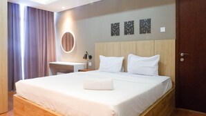A neatly made bed with white linens, a wooden headboard, and a bedside table with a lamp. - 3Br Luxurious And Elegant Apartment At Grand Sungkono Lagoon (Surabaya)
