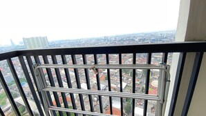 A balcony with metal railings overlooking a cityscape with buildings and a distant high-rise.