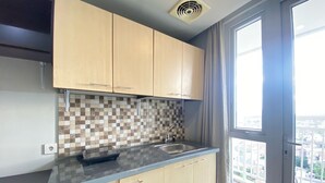 Una cocina moderna con armarios de madera clara, un salpicadero a cuadros y un amplio ventanal con vistas a la ciudad.