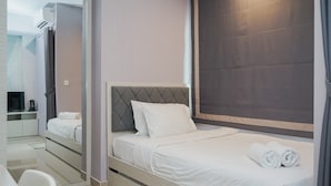 A modern hotel room with a bed, a desk, and a chair. - Fancy And Comfy Studio At B Residence Apartment (Pagedangan)
