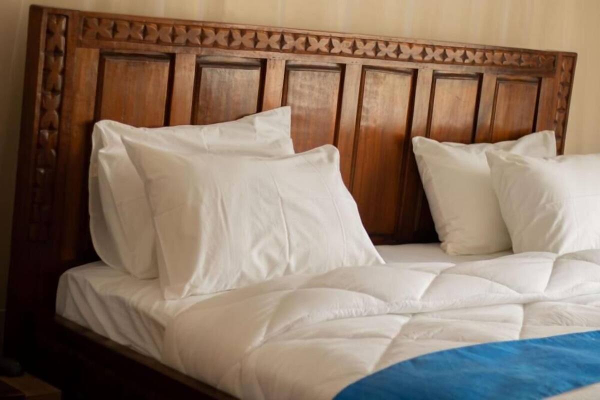 A bed with a wooden headboard and white bedding.