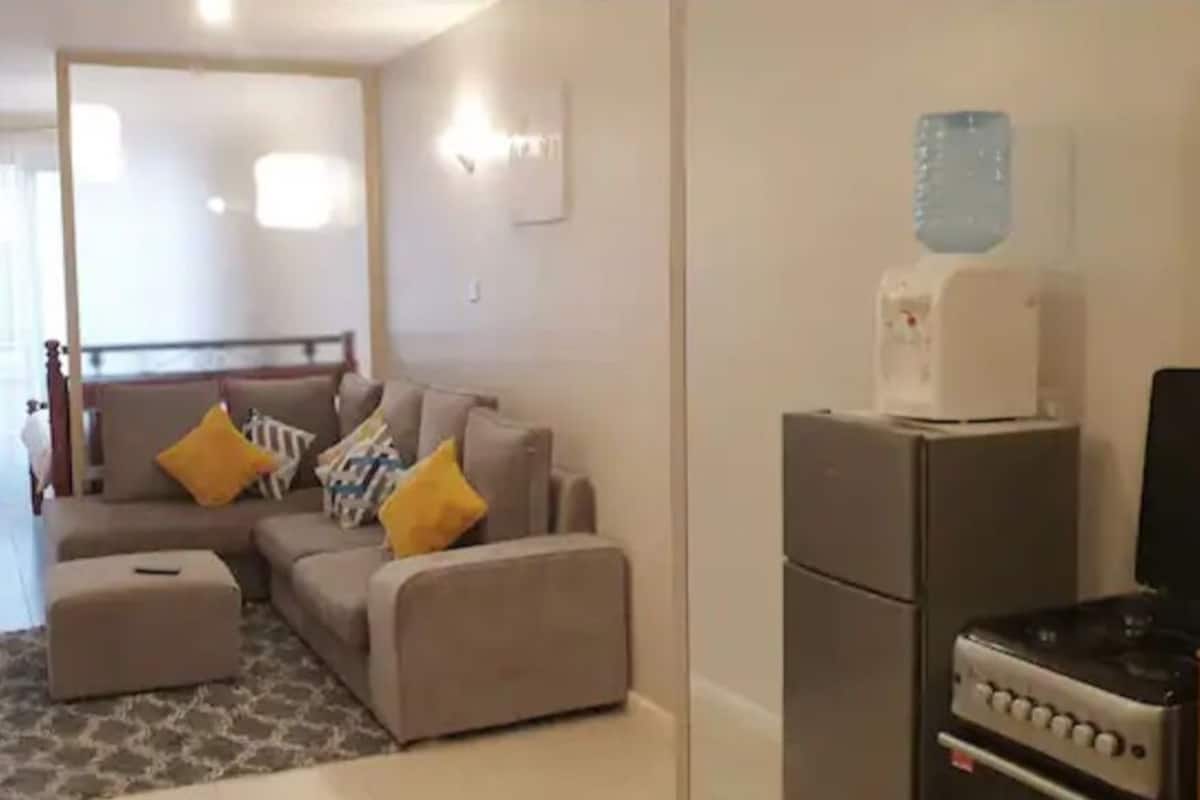 A compact living space with a sofa set, a kitchenette, and a water dispenser.