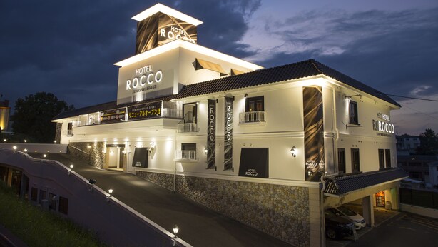 A multi-story hotel with a prominent sign reading "Hotel Rocco." It features a modern design with balconies and a stone facade.