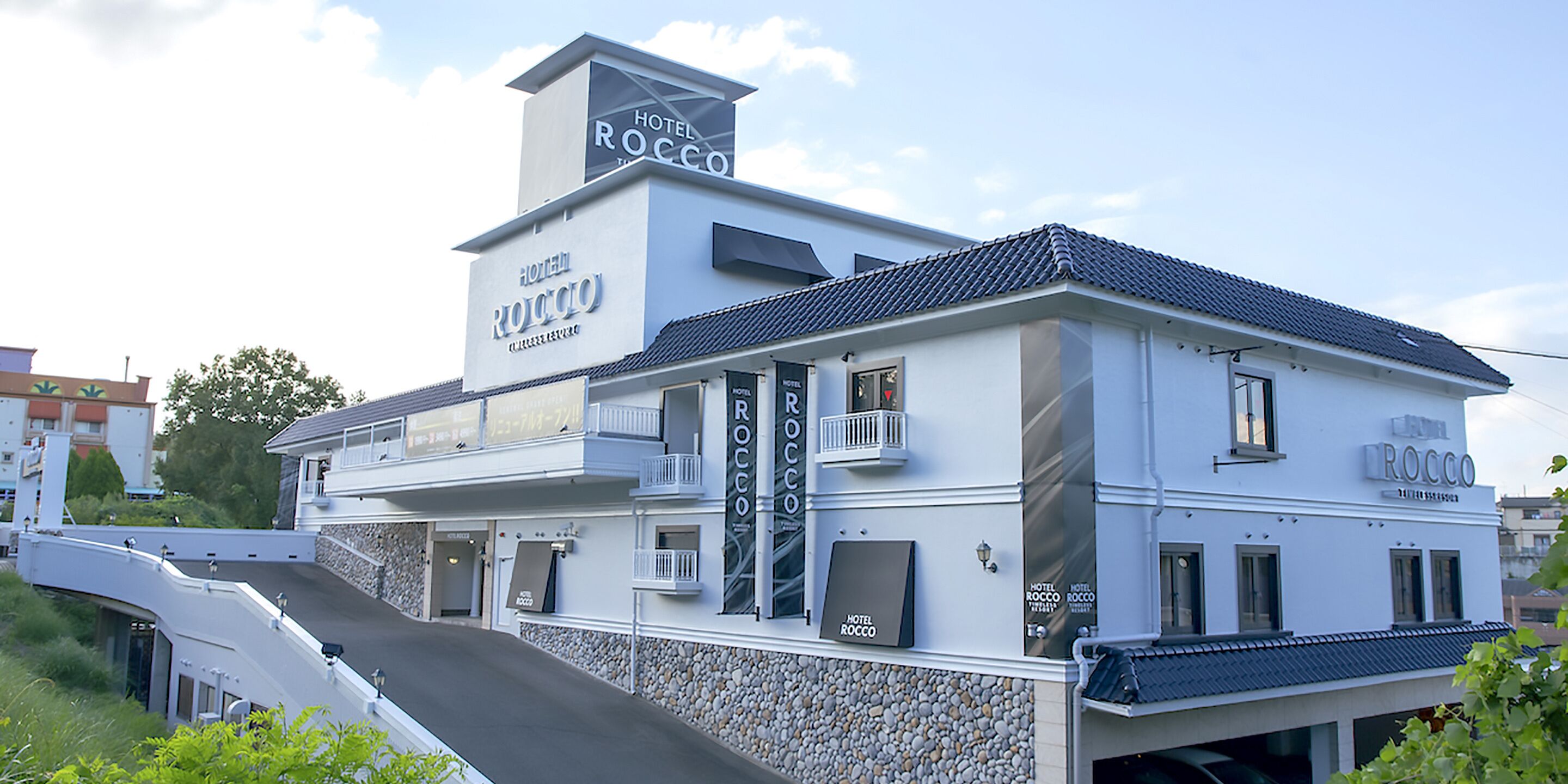 Un hotel de dos pisos llamado Hotel Rocco, con un diseño moderno, que cuenta con balcones y fachada de piedra.
