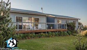 A modern house with a deck, a fenced yard, and a logo indicating pets are welcome inside.