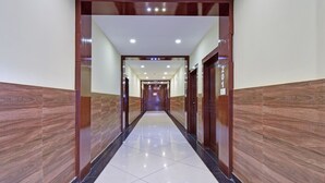 A long, narrow hallway with wooden paneling on the walls and a tiled floor. - Treebo Sky Point (Jalpaiguri)