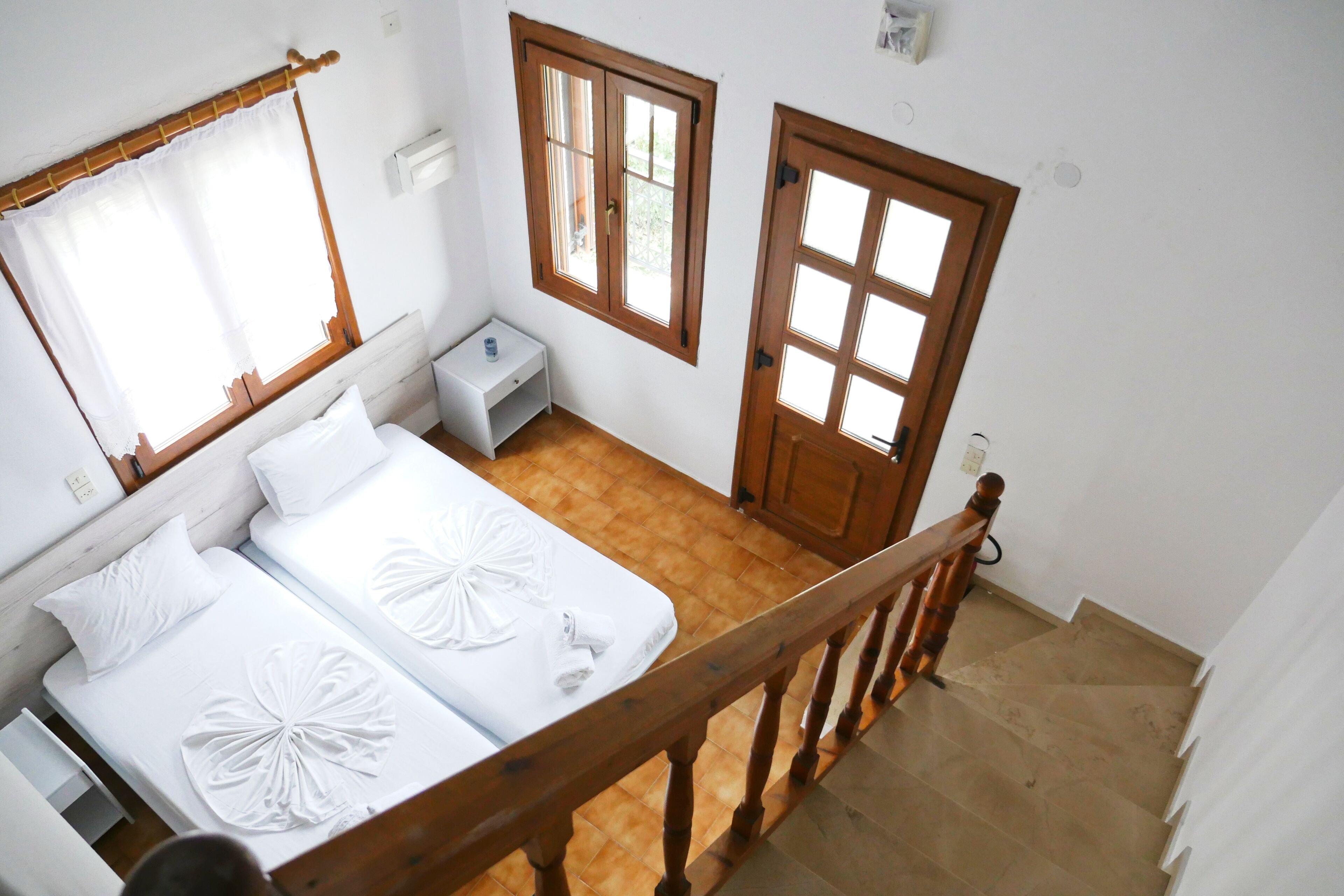 Habitación de hotel con dos camas, una escalera de madera y vistas al exterior.