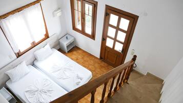 Habitación de hotel con dos camas, una escalera de madera y vistas al exterior.