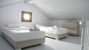 A bedroom with two beds, a dresser, and a window.