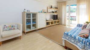 Una habitación amplia con una cama grande, un sofá, un aparador con puertas de cristal y un televisor.