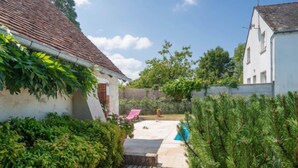 A courtyard with a wooden deck, a small pool, and lush greenery.
