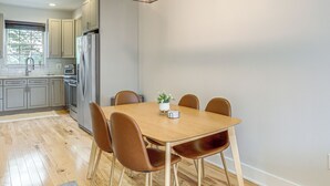 A modern kitchen with wooden cabinets, a stainless steel refrigerator, and a dining table with four chairs. - 3-Story Philly Townhouse 2 Mi to University City! (Philadelphia)