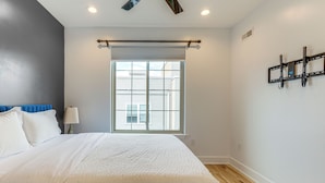 A bedroom with a bed, a window, a wall-mounted TV, and a ceiling fan. - 3-Story Philly Townhouse 2 Mi to University City! (Philadelphia)
