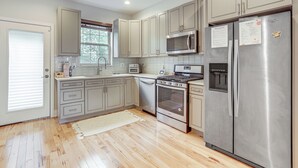 A kitchen with stainless steel appliances, light-colored cabinets, and a wooden floor. - 3-Story Philly Townhouse 2 Mi to University City! (Philadelphia)